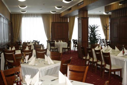 uma sala de jantar com mesas e cadeiras brancas em Hotel Elegance em Asenovgrad