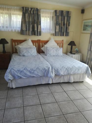 a bedroom with two beds with blue blankets and pillows at A Wave from it all in Port Shepstone