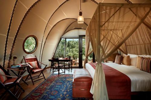 una camera con letto a baldacchino e tavolo e sedie di Wild Coast Tented Lodge All Inclusive a Yala