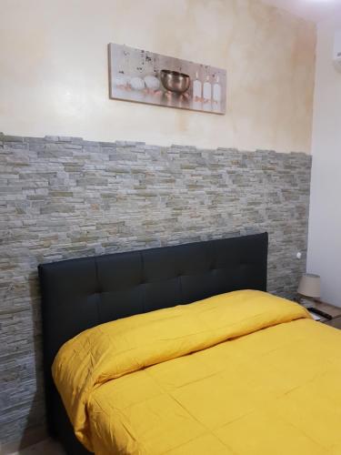 a bedroom with a yellow bed with a brick wall at B&B Dimora del centro in Scalea