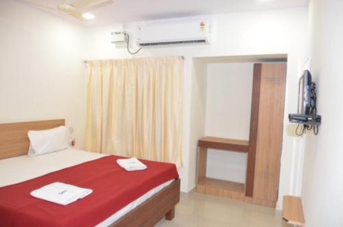 Un dormitorio con una cama con sábanas rojas y una ventana en Raya's Inn, en Kumbakonam