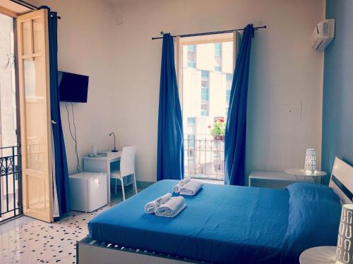 Un dormitorio con una cama azul con toallas. en Arco di Trionfo Palermo Bed & Breakfast, en Palermo