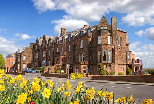 a large brick building with yellow flowers in front of it at Cairndale Hotel & Spa in Dumfries