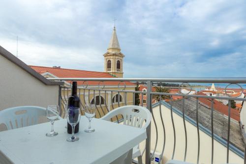 a white table with two wine glasses on a balcony at Apartments in city center Ventus in Novalja