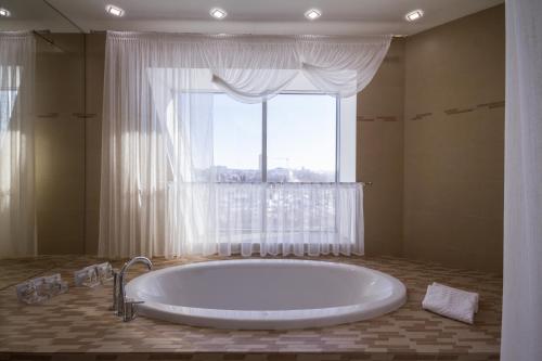 baño con bañera grande y ventana en Respublika Apart-hotel, en Cheboksary