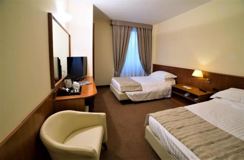 a hotel room with two beds and a chair at Best Western Park Hotel in Piacenza
