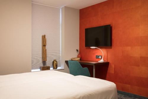 a bedroom with a bed and a desk with a tv at Hotel de Koppelpaarden in Lichtenvoorde