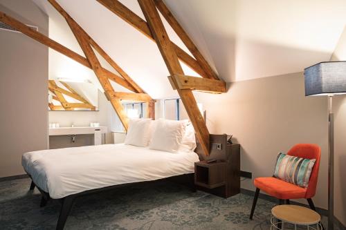 a bedroom with a white bed and a red chair at Hotel de Koppelpaarden in Lichtenvoorde