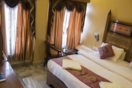 a hotel room with two beds and two windows at Hotel Temple On Ganges in Varanasi