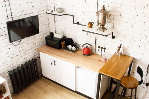 a kitchen with a wooden counter and a tv on a white brick wall at Matryoshka apartment in Khabarovsk