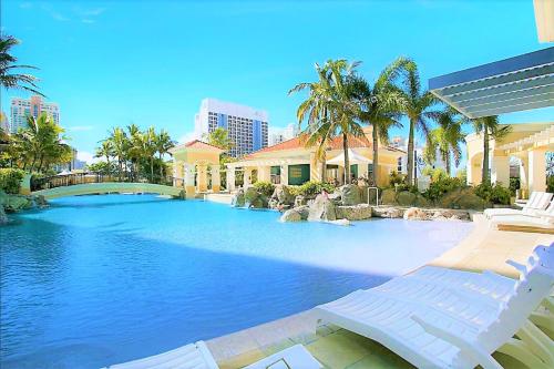 a large swimming pool with two lounge chairs and palm trees at The Towers of Chevron Renaissance - Holidays Gold Coast in Gold Coast