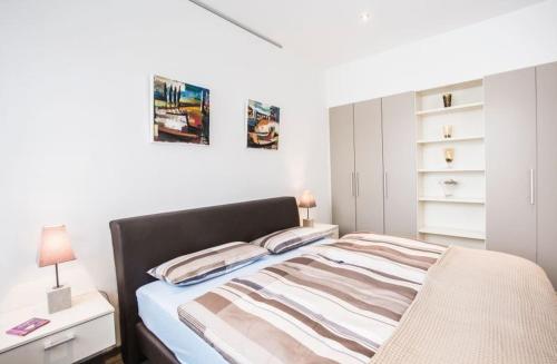 a white bedroom with a bed and a night stand at Apartments by Intermezzo in Albstadt