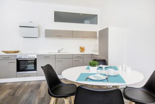 a kitchen with a white table and black chairs at Apartments by Intermezzo in Albstadt