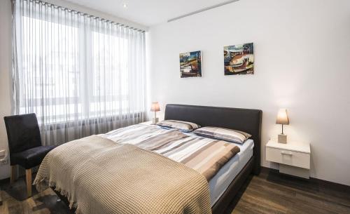 een slaapkamer met een bed, een stoel en een raam bij Apartments by Intermezzo in Albstadt