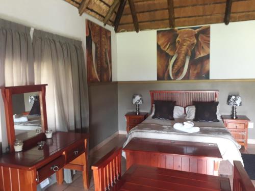 a bedroom with an elephant picture on the wall at Pepe Piatto Lodge in Grootvlei