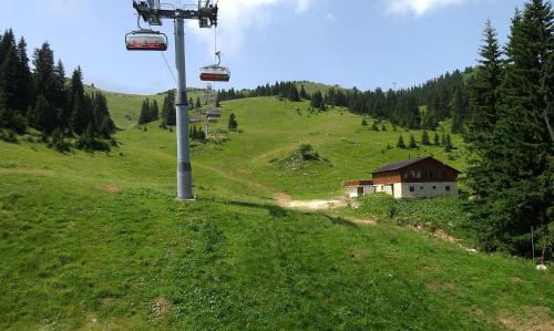 a ski lift on a green hill with a house at Apartmani Marija in Jahorina