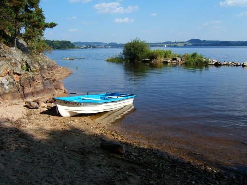 a small boat sitting on the shore of a lake at Penzion Stříbrný vítr in Horní Planá