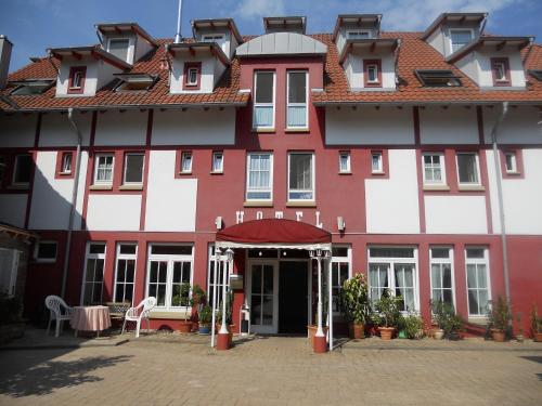 a large red and white building with a courtyard at Cross-Country-Hotel Hirsch in Sinsheim