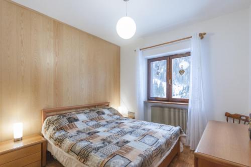 sypialnia z łóżkiem i oknem w obiekcie Condominio Val Biois 7 w mieście Falcade