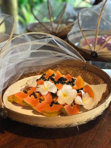 Un plato de comida con fruta y flores sobre una mesa. en Pousada Barra Trip, en Barra Grande