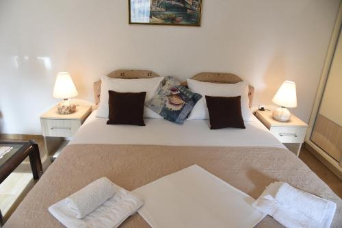 a bedroom with a large white bed with two lamps at Apartments & Rooms Jelka in Kotor