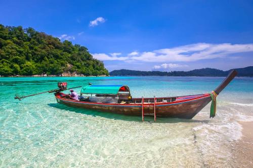 a boat sitting in the water on a beach at Secret Garden Family House in Ko Chang
