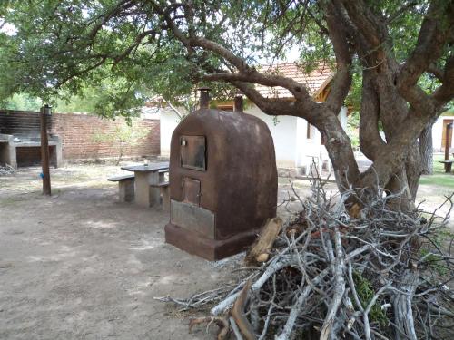 an old stove sitting under a tree next to a table at Algarrobo Luz Cabañas in Capilla del Monte