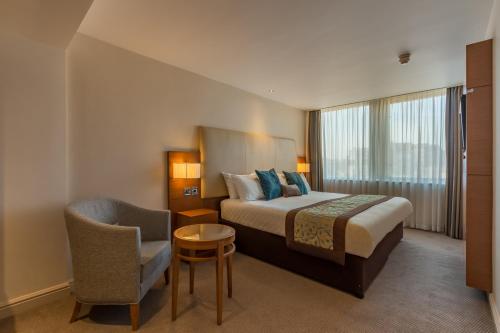 a hotel room with a bed and a chair at Thistle Trafalgar - Leicester Square in London