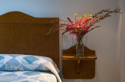 a vase of flowers on a table next to a bed at Apartamentos La Cruz de Paderne in Navia