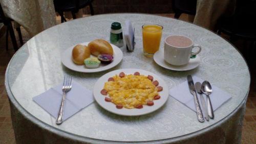 a table with two plates of breakfast food and a cup of orange juice at Hotel Popayan Plaza in Popayan
