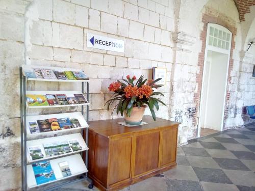 a refrigerator and a vase with flowers on a table at Domaine De Sery in Bouttencourt
