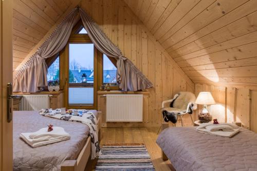 a bedroom with two beds and a window at Chaty Zakopane in Zakopane