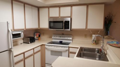 a kitchen with white cabinets and a sink and a microwave at JeffsCondos - 3 Bedroom - Breakers Resort in Myrtle Beach