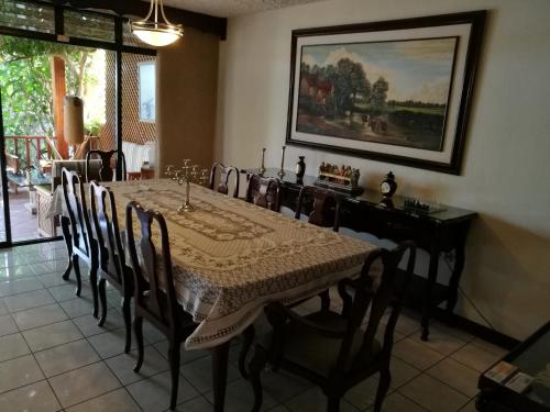 una sala da pranzo con tavolo, sedie e un dipinto di Casa familiar La Arboleda a Guatemala