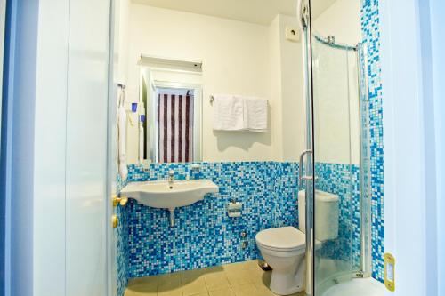 a blue tiled bathroom with a toilet and a sink at Hotel Kopala in Tbilisi City