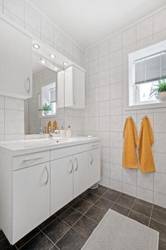 a white bathroom with a sink and a mirror at Modern apartment Tromsø in Tromsø