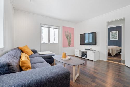 een woonkamer met een blauwe bank en een tv bij Modern apartment Tromsø in Tromsø