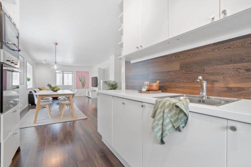 een keuken met witte kasten en een houten muur bij Modern apartment Tromsø in Tromsø