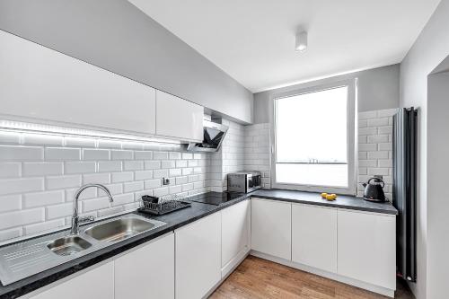 a white kitchen with a sink and a window at ORION Downtown Apartment by PinPoint in Łódź