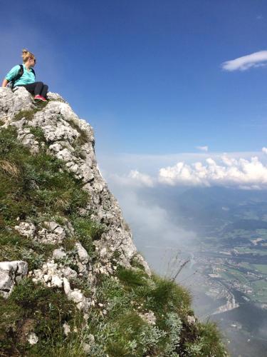 a woman sitting on the edge of a mountain at Bergbach in Ramsau