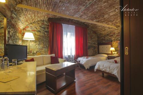 a living room with two beds and a couch and a tv at Hotel Aktaion Syros in Ermoupoli