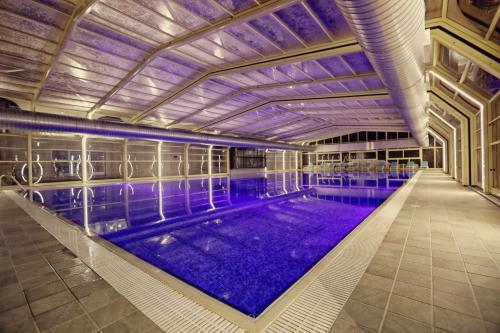 a large swimming pool with purple water in a building at Premium Beach Hotel in Golem