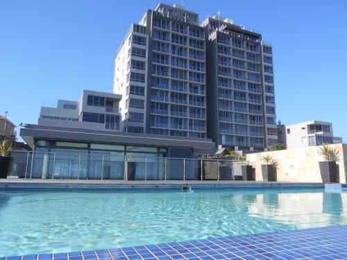 a swimming pool in front of a large building at 101Infinity in Bloubergstrand