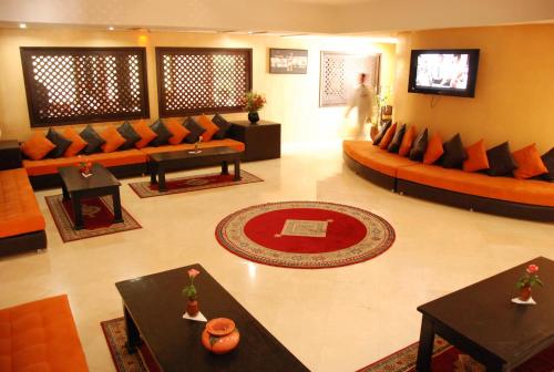 a living room with couches and tables and a television at New Farah Hotel in Agadir