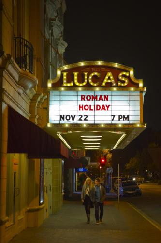 two people walking down a sidewalk under a neon sign at River Street Inn in Savannah