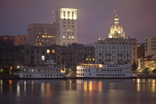a city with two boats in the water at night at River Street Inn in Savannah