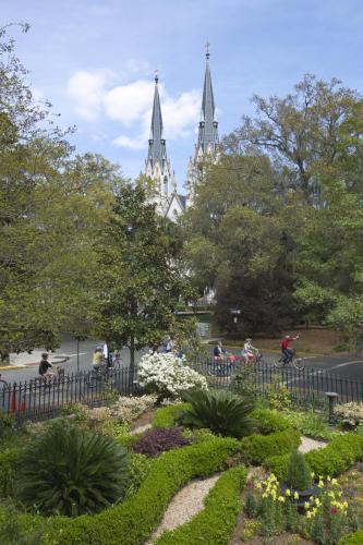 a garden in front of a church with two towers at River Street Inn in Savannah