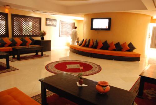 a living room with couches and a tv on the wall at New Farah Hotel in Agadir
