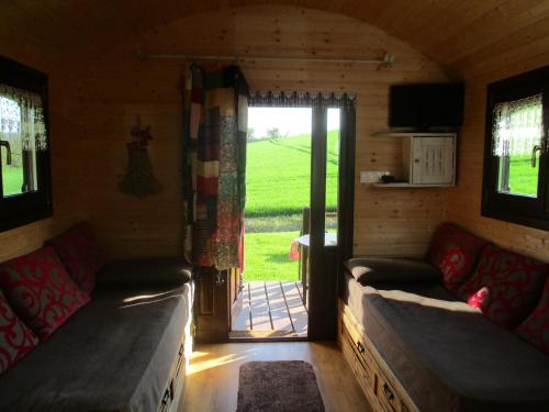 - un salon avec deux canapés et une porte coulissante en verre dans l'établissement Roulotte panoramique du Moulin, à Châtillon-sur-Marne