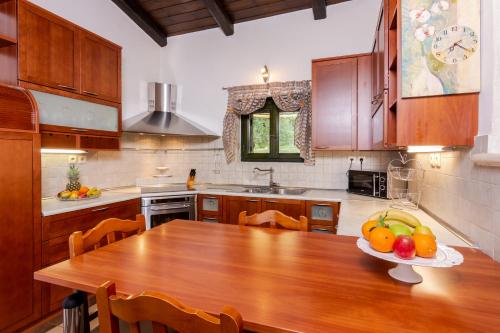 a kitchen with a wooden table with a bowl of fruit on it at Xigia Beach Residence villas in Orthoniaí